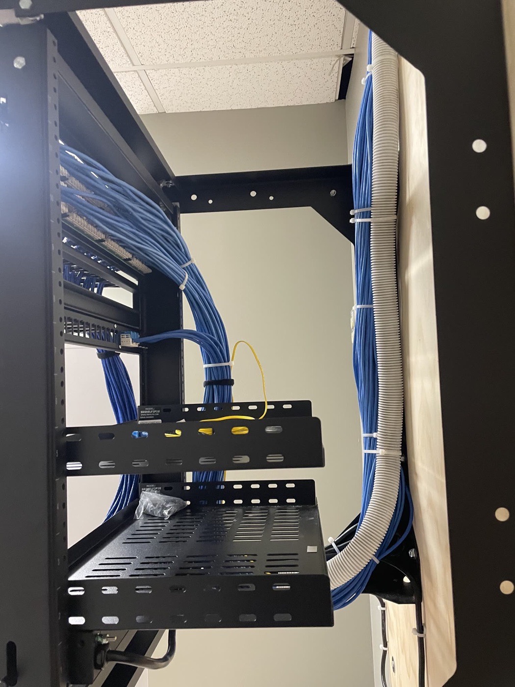 Split-loom protected cable bundles routed into a wall rack